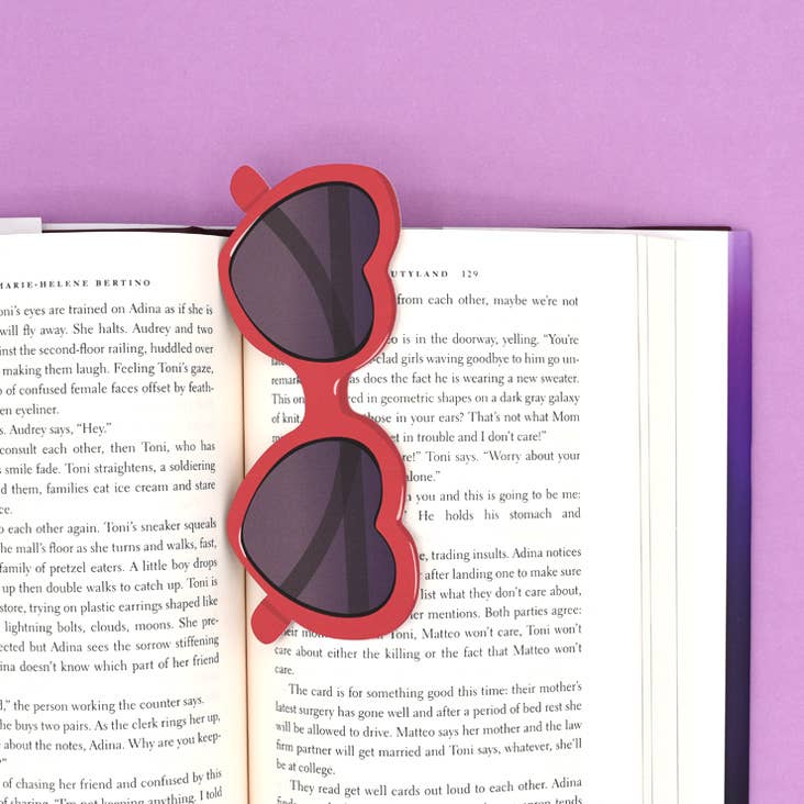 Red sunglasses-shaped bookmark on an open book with a purple background