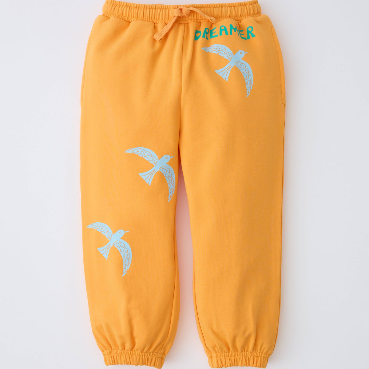 Yellow jogger pants with a drawstring waist, featuring light blue bird graphics and the word 'DREAMER' in teal on the upper thigh, shown against a plain white background.