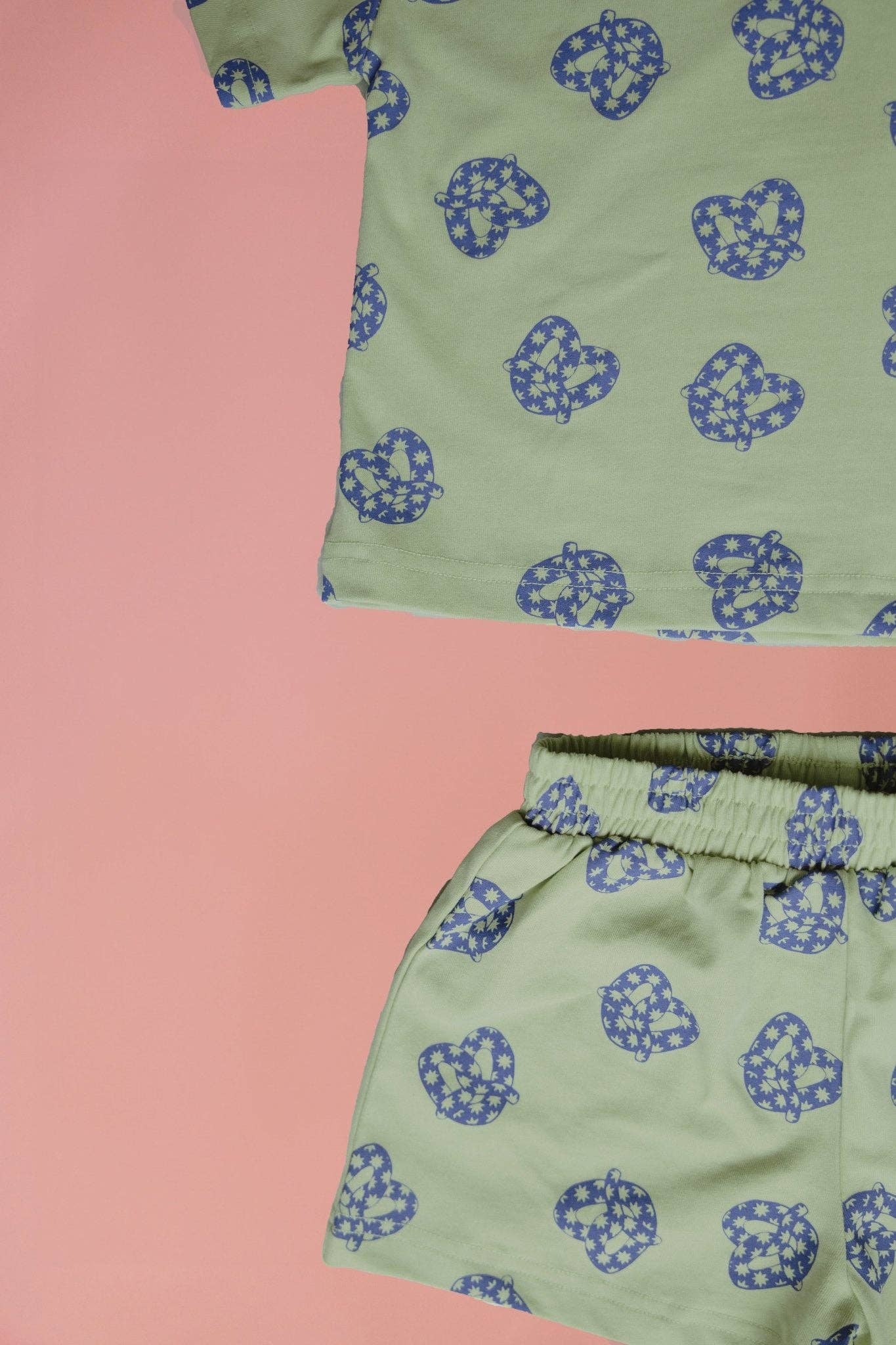 Green shirt and shorts with blue pattern on a pink background