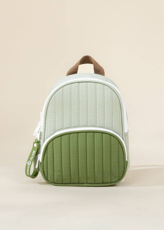 Green and white backpack with brown handle on a beige background