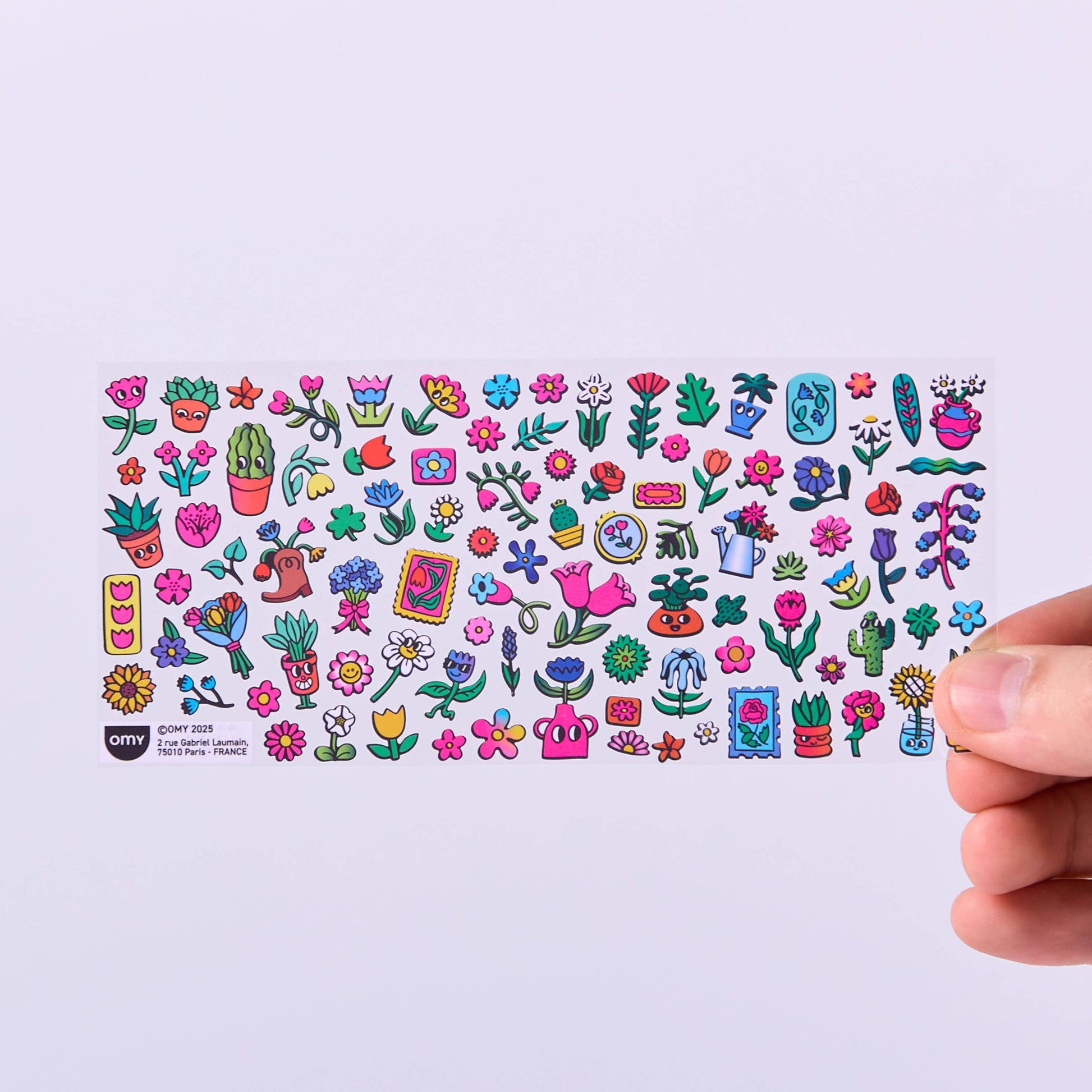 Collection of colorful stickers on a white card held by a hand against a light purple background