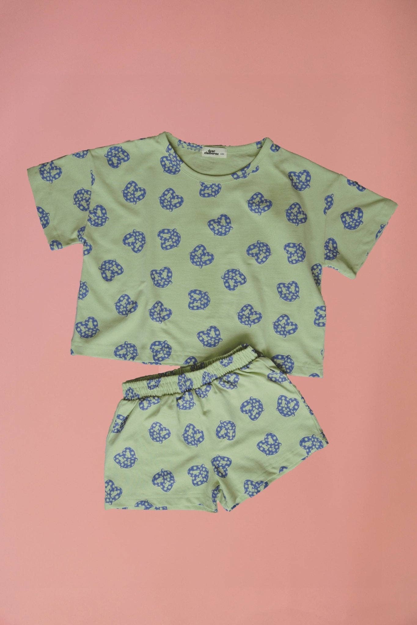 Green clothing set with blue floral pattern on a pink background