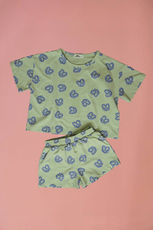 Green clothing set with blue floral pattern on a pink background
