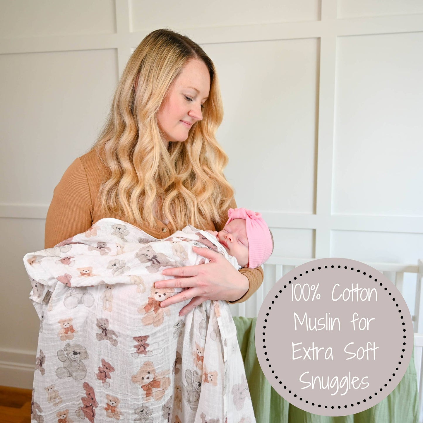 Woman holding a baby wrapped in a soft blanket with teddy bear pattern, in a home setting.
