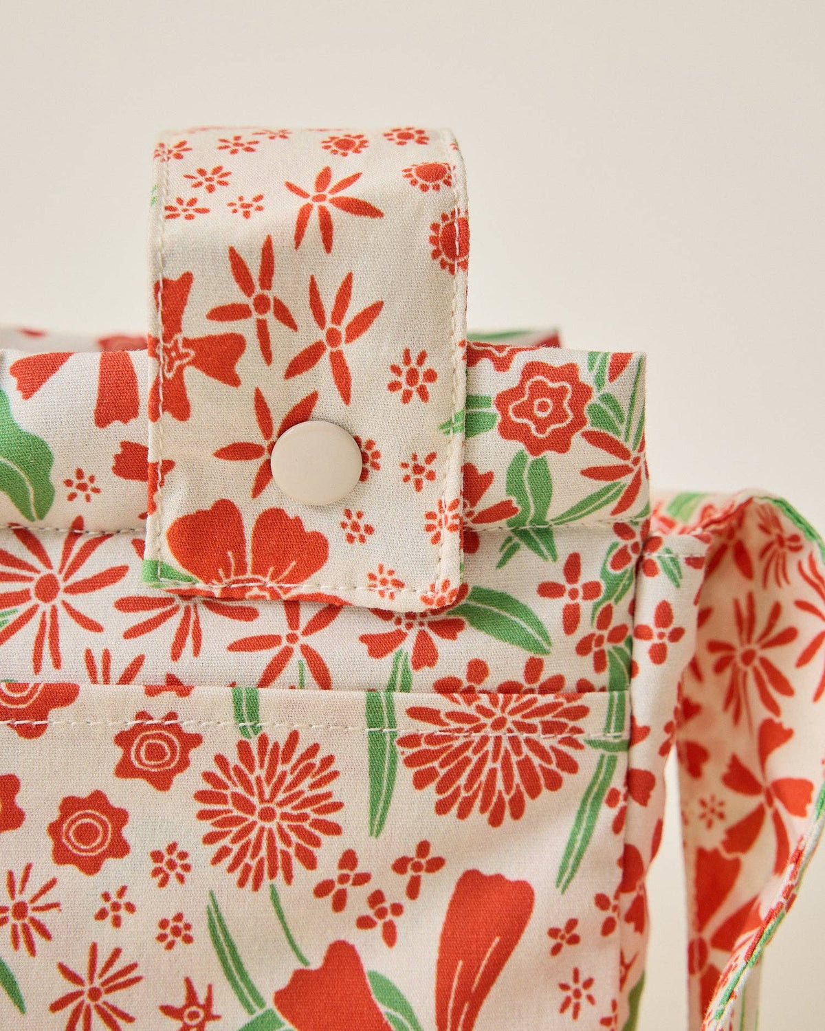 Floral-patterned fabric with red and green flowers on a beige background
