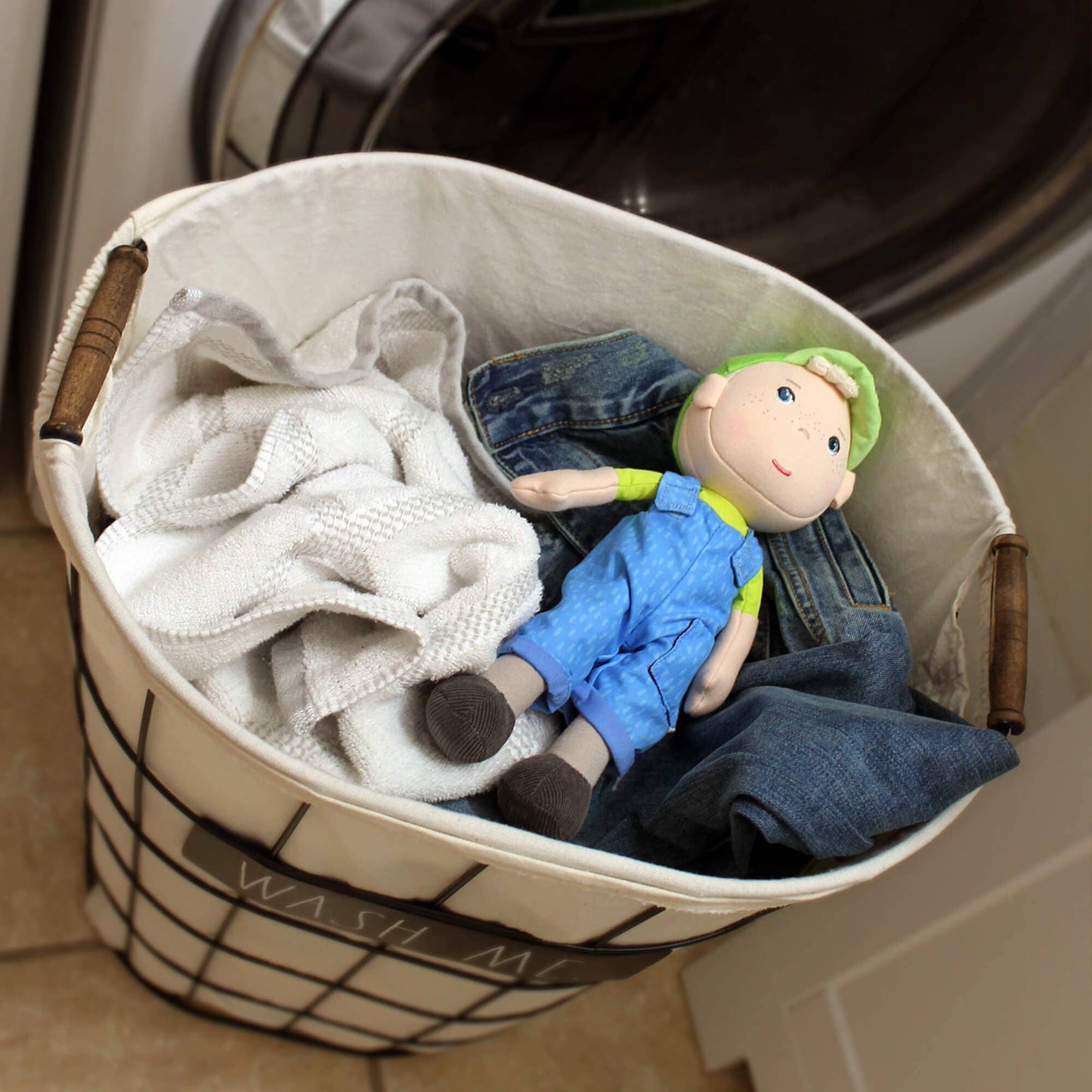 Laundry basket with clothes and a doll in front of a washing machine