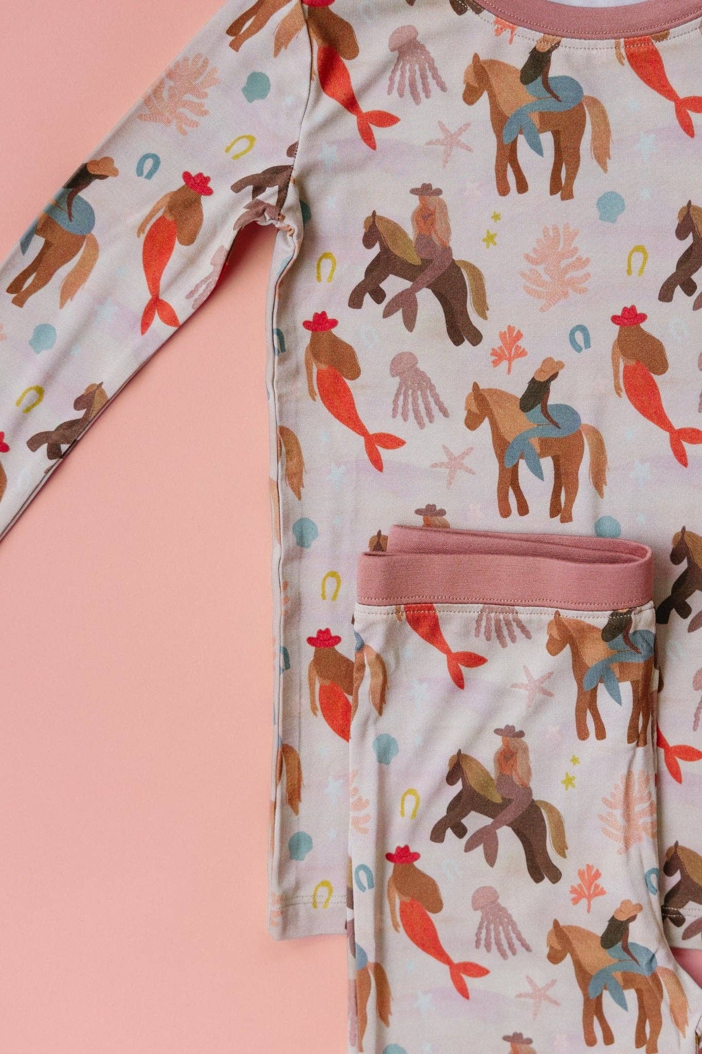 Children's pajama set with horse and mermaid pattern on a pink background