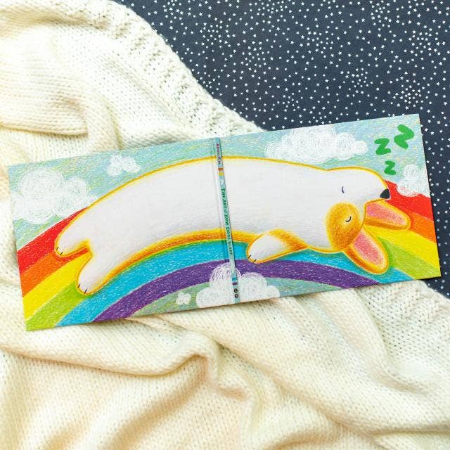 Colorful bookmark with a cartoon bear and rainbow design on a textured fabric background