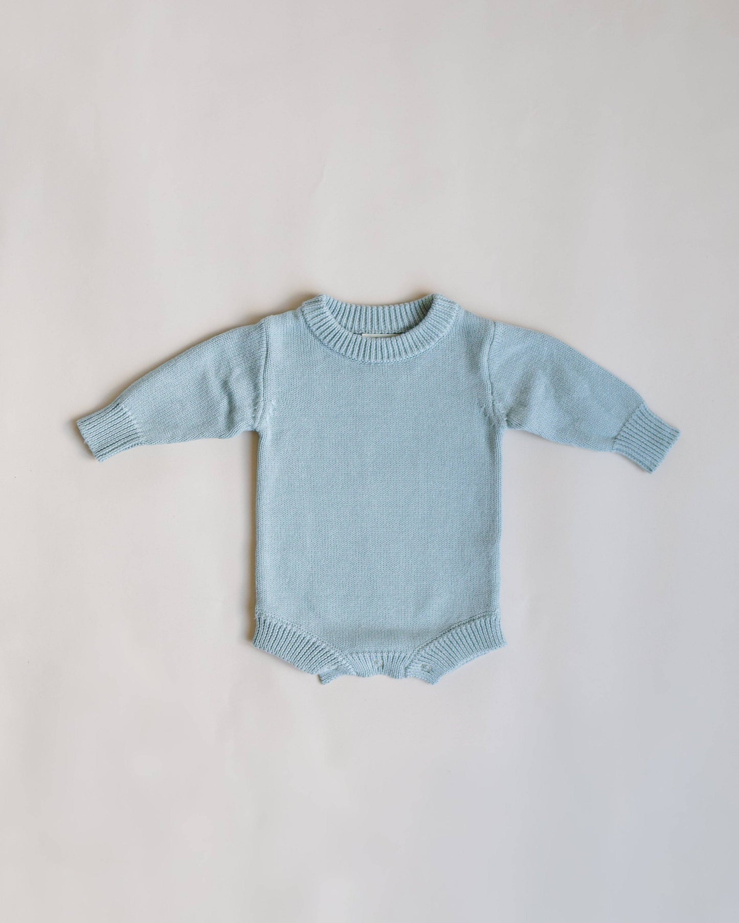 Light blue baby sweater on a light gray background