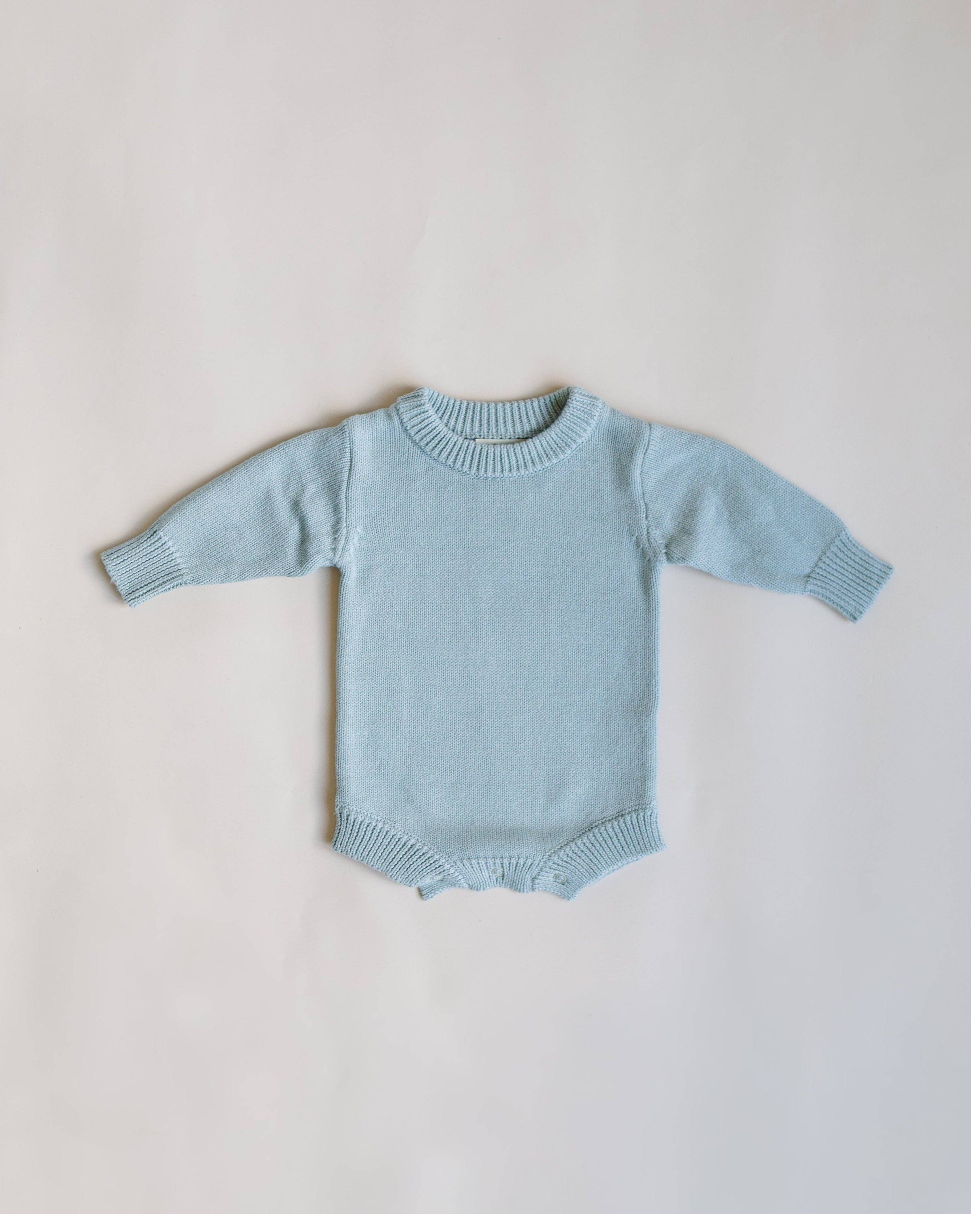 Light blue baby sweater on a light gray background