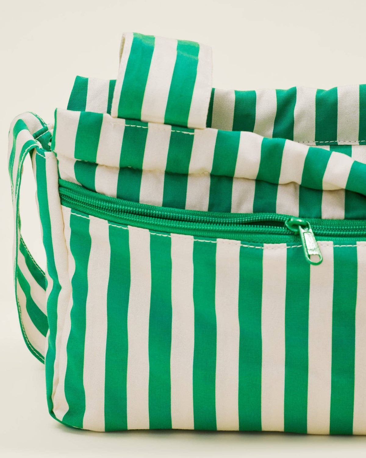 Green and white striped bag with a zipper on a light background