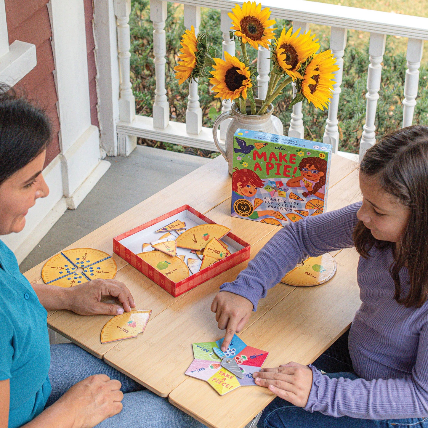 Two people playing a game on a table with sunflowers in the background