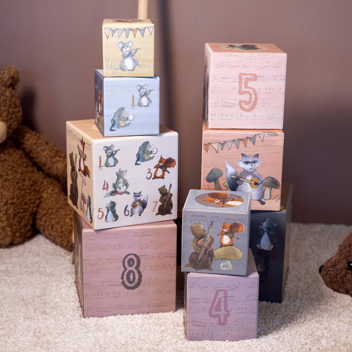 Stack of coated paper blocks with animal illustrations and numbers, next to a teddy bear.