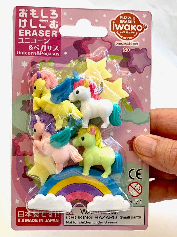 Packaged puzzle erasers with unicorns and pegasus on a pink background, held by a hand.