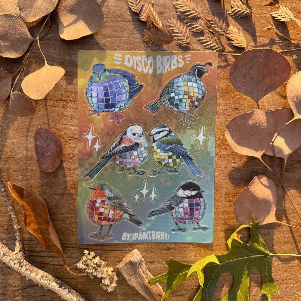 Sticker with mosaic disco ball style birds on a wooden surface with leaves